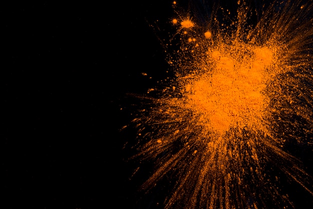 Une explosion de poudre orange sur fond noir.