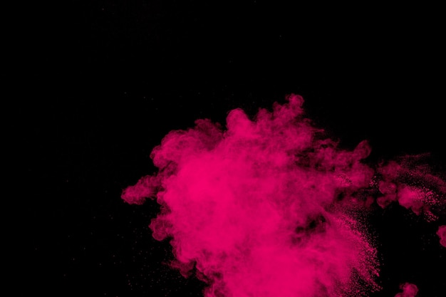 Photo explosion de poudre rose sur fond noir nuage d'éclaboussures de poussière rose sur fond sombre