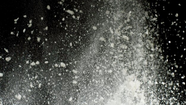 Explosion de poudre sèche blanche avec chute de poussière blanche isolée sur fond noir