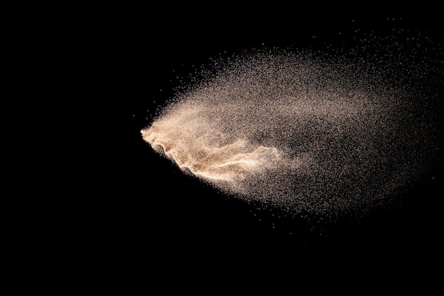 Explosion de sable doré isolé sur fond noir.