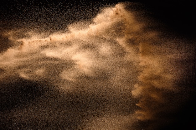 Explosion de sable doré isolée sur fond noir.