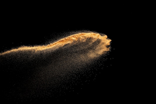 Explosion de sable isolée sur fond noir Mouvement de gel des éclaboussures de poussière de sable