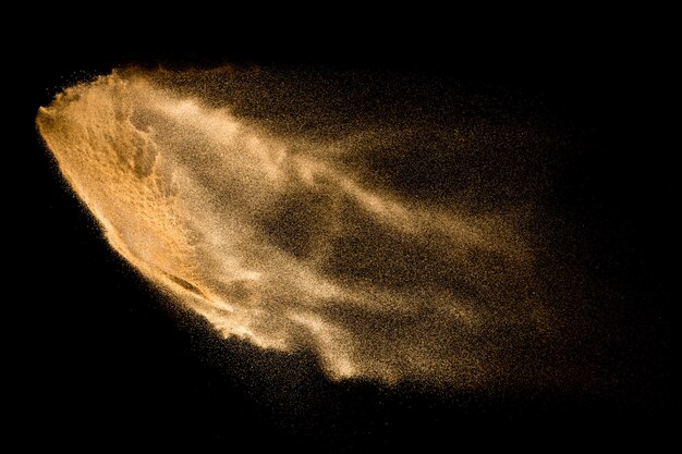 Explosion de sable jaune isolée sur fond noir.