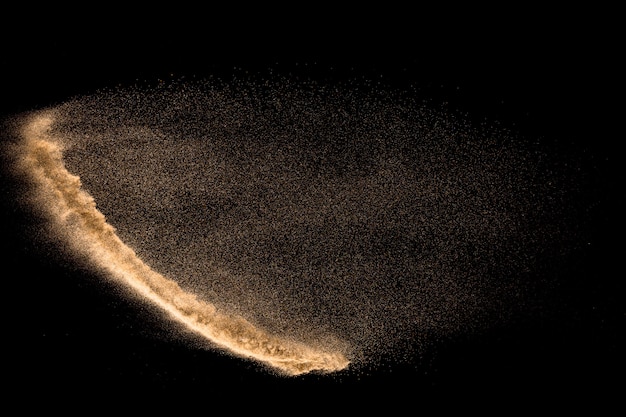 Explosion de sable de rivière à sec. Éclaboussure de sable couleur marron sur fond noir.