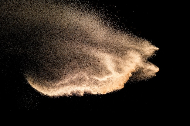 Explosion de sable de rivière à sec. Éclaboussure de sable de couleur marron sur fond noir.