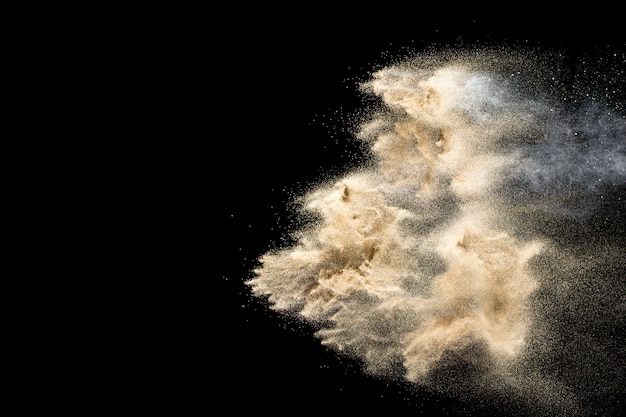 Explosion de sable de rivière à sec. Éclaboussure de sable doré sur fond noir.