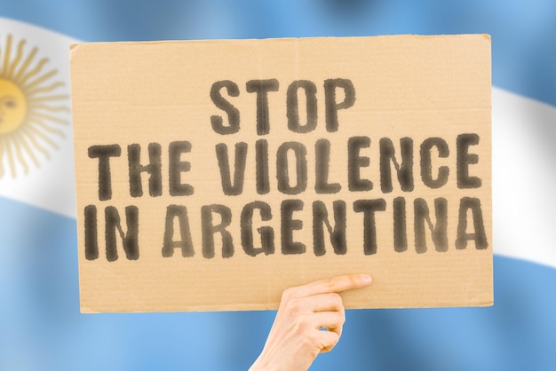 L'expression Arrêtez la violence en Argentine est sur une bannière entre les mains des hommes avec un drapeau argentin flou en arrière-plan Triste Droits Sécurité Social Stress Combat Haine Cruauté