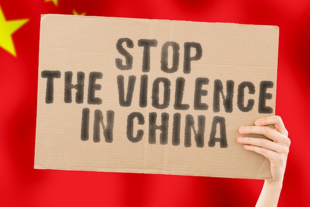 L'expression Arrêtez la violence en Chine est sur une bannière entre les mains des hommes avec un drapeau chinois flou en arrière-plan Triste Droits Sécurité Social Stress Combat Haine Cruauté Furieux Frapper