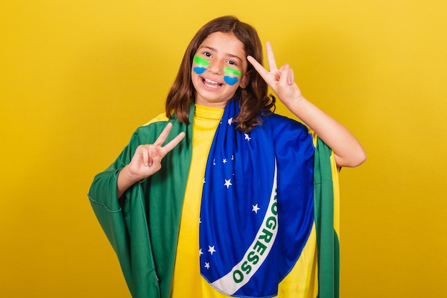 L'expression de l'enfant de race blanche brésilienne de la paix et de l'amour les doigts levés pose heureuse pour la photo de fan de football aux Jeux Olympiques de la Coupe du Monde