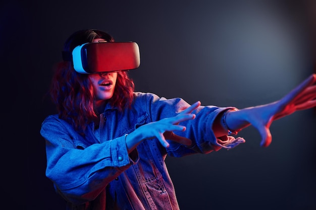 Expression faciale de jeune fille avec des lunettes de réalité virtuelle sur la tête en néon rouge et bleu en studio