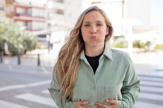 Avec une expression folle et surprise, les joues gonflées, se sentant grosses et pleines de nourriture.