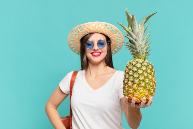 Expression heureuse de femme jeune voyageur et tenant un ananas