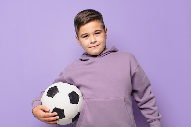 Expression heureuse de petit garçon et tenant un ballon de football