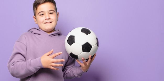 Expression heureuse de petit garçon et tenant un ballon de football