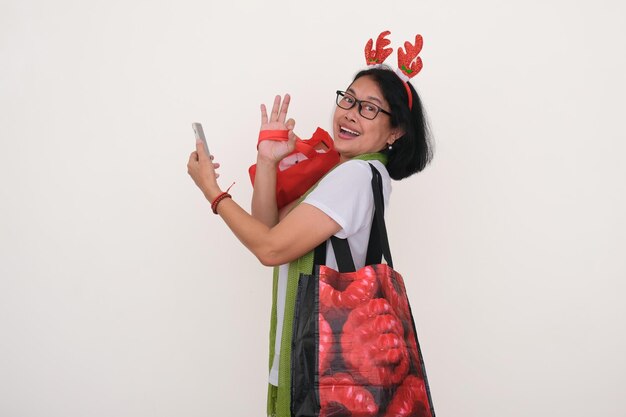 L'expression joyeuse d'une femme asiatique après avoir fait ses courses de Noël avec beaucoup de sacs à la main