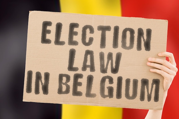 L'expression loi électorale en Belgique sur une bannière entre les mains des hommes avec un drapeau belge flou en arrière-plan Constitution Sénat politique Majorité électorale de Bruxelles