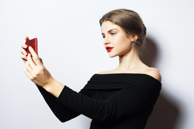 Expressions d'émotions et concept de personnes heureuse souriante jeune femme portant une robe noire prenant selfie avec smartphone