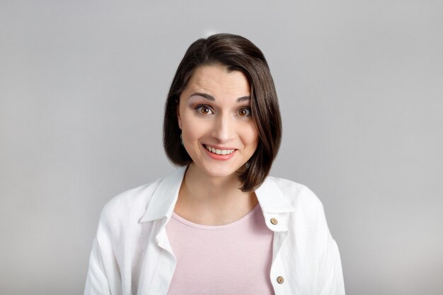 Expressions et émotions du visage humain Portrait de jeune femme brune en réservoir rose et chemise blanche