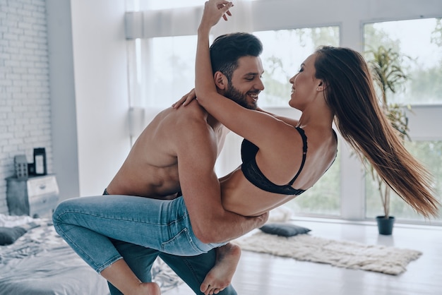 Exprimer l'amour avec la danse. Beau jeune couple embrassant et souriant en dansant dans la chambre