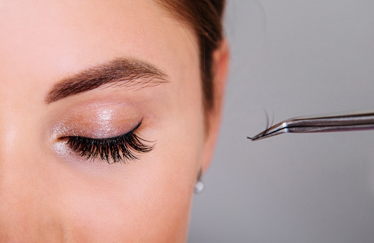 Photo extension de cils belle femme yeux gros plan et pincettes