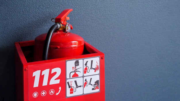 Photo extincteur rouge dans la boîte d'urgence contre le mur gris