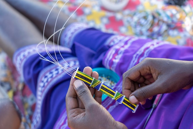 Fabrication de bijoux artisanaux femmes africaines Masai mains vue de dessus close up île de Zanzibar Tanzanie Afrique