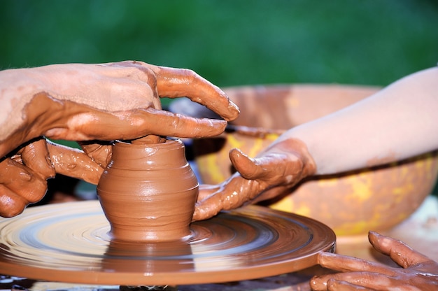 Fabrication de poterie traditionnelle, gros plan sur les mains du potier façonnant un bol