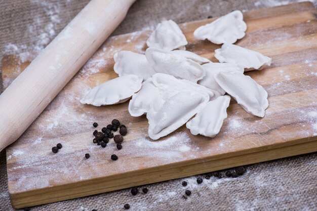 Fabrication de raviolis ou de raviolis de boulettes de pâte maison. Modèle pour pâtes faites maison fourrées de viande. Préparer un repas bio sur un bureau en bois.