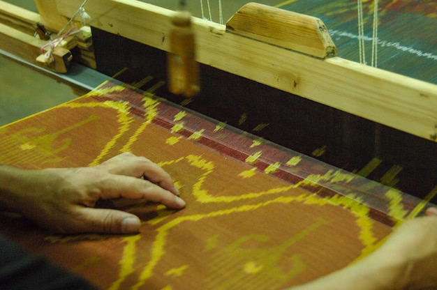 Fabriqué à la main sur un métier à tisser en bois fabrication de gros plan de fil et de tissu