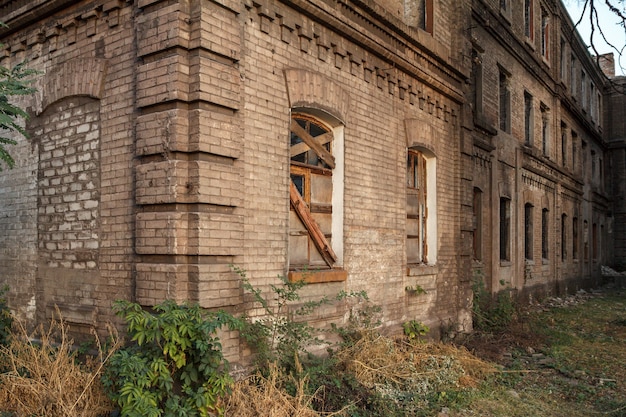 Façade de l'ancien bâtiment en brique abandonné avec fenêtre bordée de planches de bois