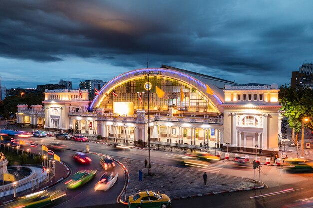 Façade antique de la gare de Hua Lamphong illuminée par une voiture et un rond-point dans un endroit sombre à Bangkok