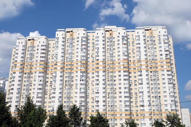 Façade d'un bâtiment résidentiel beige moderne sur un ciel bleu avec des nuages blancs