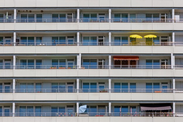 Photo façade d'un grand immeuble d'appartements avec des parapluies jaunes sur l'un des balcons