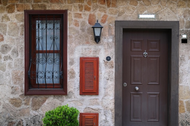 Façade d'une maison avec une fenêtre avec un cadre en bois une porte en bois et des lanternes vintage