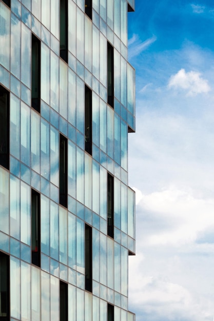 Photo une façade moderne en verre et en acier sur un fond de ciel bleu et de nuages