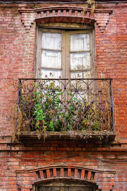 Façade de vieille brique et maison abandonnée avec des plantes sèches sur le balcon
