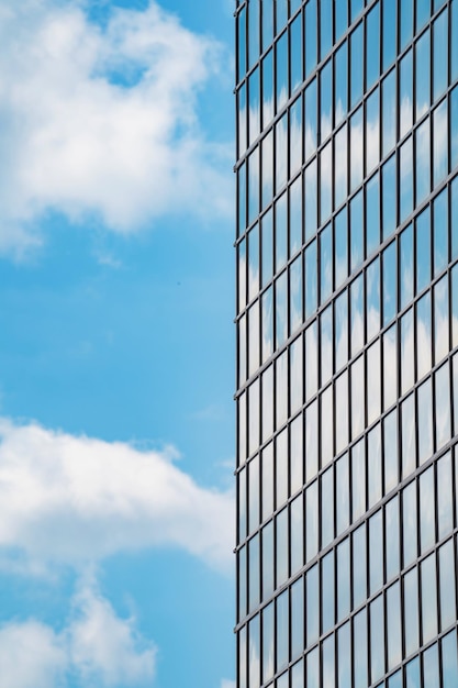 Façade vitrée d'un immeuble de grande hauteur contre un ciel bleu avec des nuages