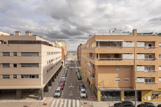 Façades d'immeubles résidentiels et de rues avec des voitures en stationnement un jour de nuages d'orage