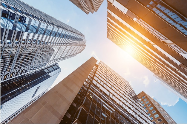 Façades en verre de gratte-ciel par une belle journée ensoleillée avec des rayons de soleil dans le ciel bleu.