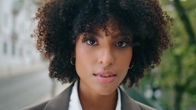 Face de fille sensuelle regardant la caméra avec un sourire léger portrait de femme bouclée en gros plan