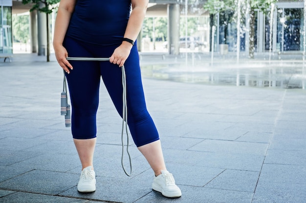 Faceless Plus size sinueuse heureuse jeune femme avec une corde à sauter à l'extérieur