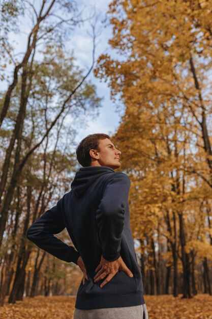 Faible angle de sportif faisant de l'exercice et s'étirant tout en s'entraînant par une journée ensoleillée dans le parc d'automne