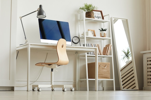 Faible angle de vue au travail de bureau à domicile tout blanc avec chaise en bois et ordinateur moderne sur 24