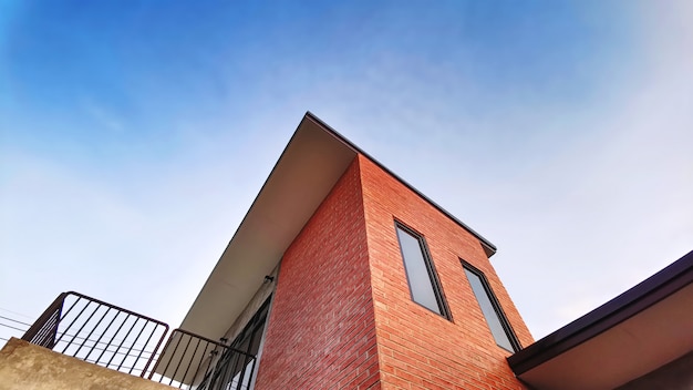 Faible angle de vue du bâtiment avec balcon décoré de briques contre le ciel bleu