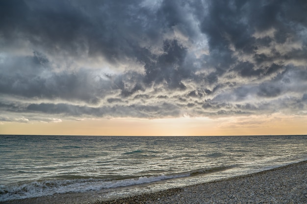 De faibles nuages d'orage flottent au-dessus de la mer, offrant une vue sur le coucher de soleil