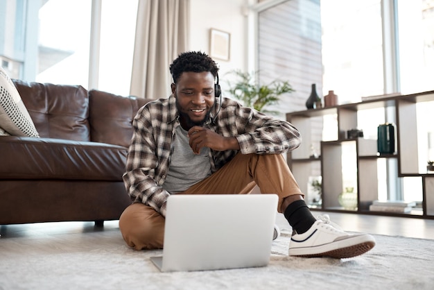 Faire des affaires d'où il est le plus confortable Photo d'un jeune homme portant un casque tout en travaillant sur un ordinateur portable à la maison