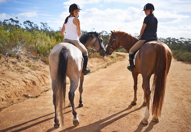 Faire une balade Vue arrière de deux femmes à cheval