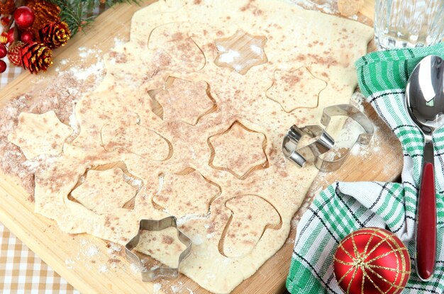 Faire des biscuits de Noël sur planche de bois sur la surface de la nappe