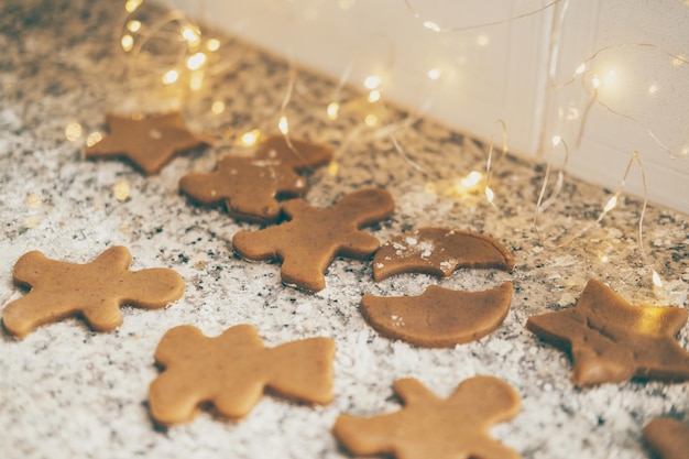 Faire des biscuits de Noël traditionnels des biscuits au pain d'épice sur la table de la cuisine avec des lumières de Noël