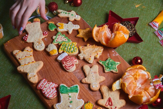 Faire bonhomme de pain d'épice, pâte à biscuits. Le concept d'une fête dans la maison, un dîner en famille. Concept de traditions du nouvel an et processus de cuisson. Cookies sur table verte en bois.